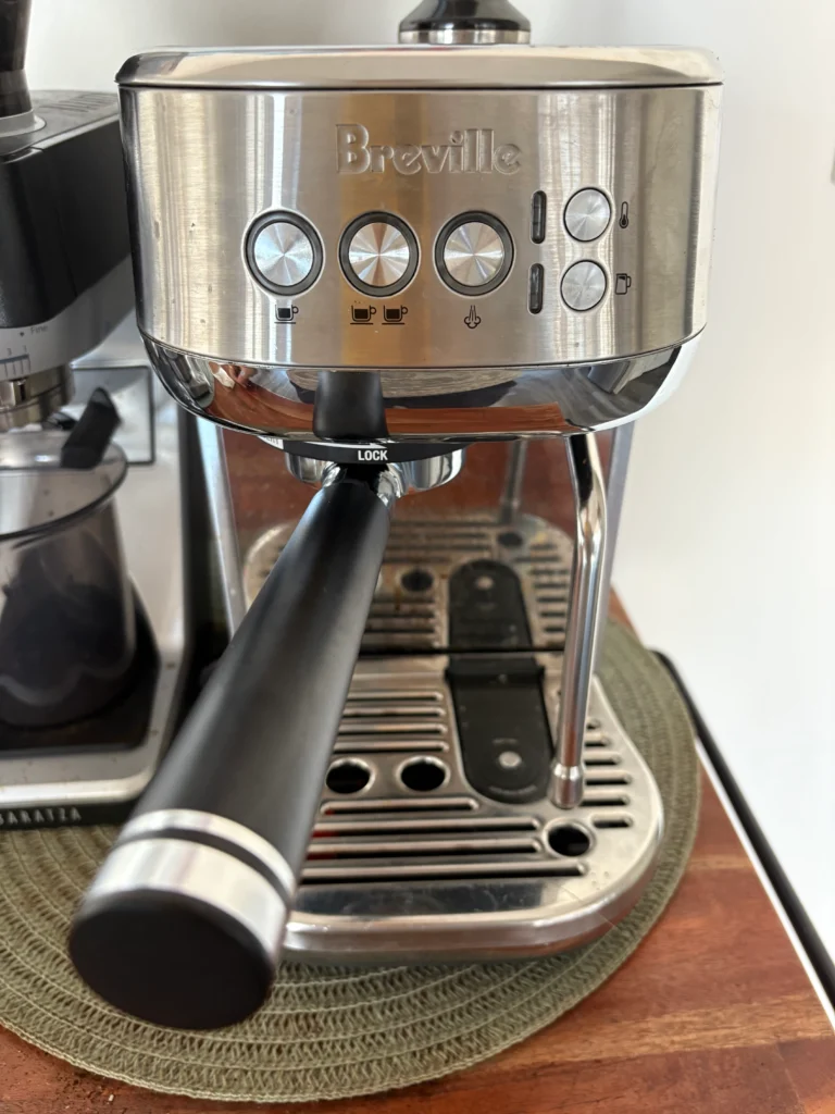 Breville Bambino Plus espresso machine with a metal-handled bottomless portafilter attached.